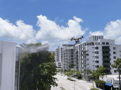 A drone cleaning the exterior of a white building sprays water