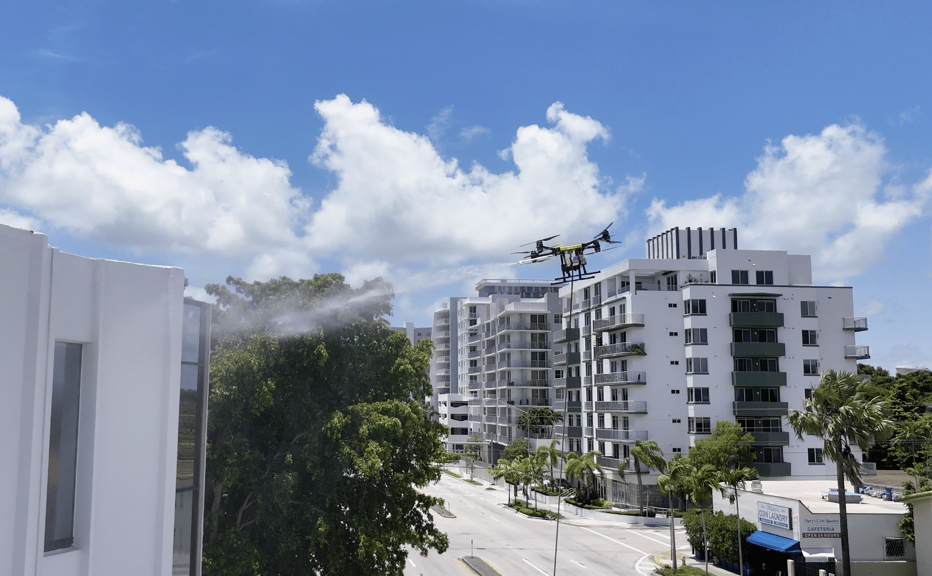 A drone cleaning the exterior of a white building sprays water